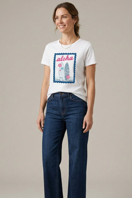 Woman wearing a white t-shirt with a graphic design and blue jeans on a plain background