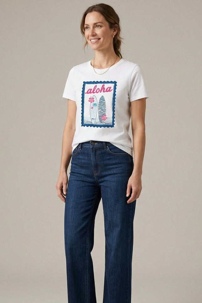 Woman wearing a white t-shirt with a graphic design and blue jeans on a plain background